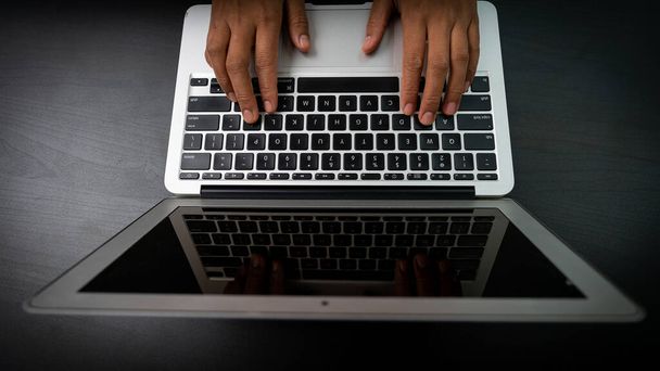 Τα χέρια πιέζουν το πληκτρολόγιο στο φορητό υπολογιστή για να εργαστούν και να αναζητήσουν πληροφορίες μέσω του Διαδικτύου. - Φωτογραφία, εικόνα