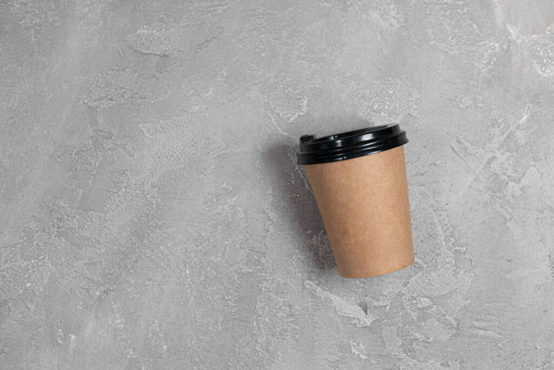 Blank take away coffee paper cup isolated on a gray concrete background. - Photo, Image