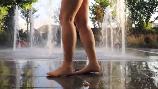 Menina descalça jogando na fonte de água fria em um dia quente de verão - Filmagem, Vídeo