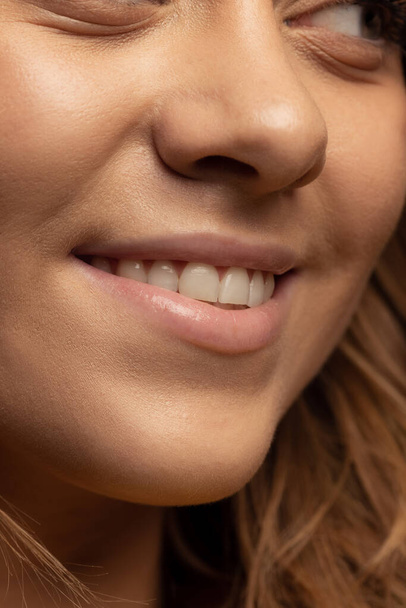 Обрезанное изображение улыбающегося женского лица с нежной загорелой кожей. Естественная женская красота - Фото, изображение