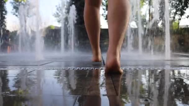 Menina descalça jogando na fonte de água fria em um dia quente de verão - Filmagem, Vídeo