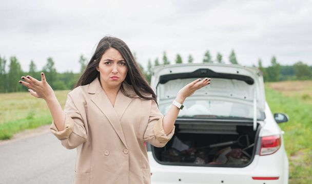 Donna stressata in piedi vicino rotto auto sulla strada all'aperto - Foto, immagini