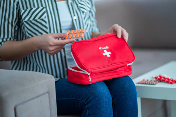 A woman holds a medical first aid kit with medicine at home - Valokuva, kuva
