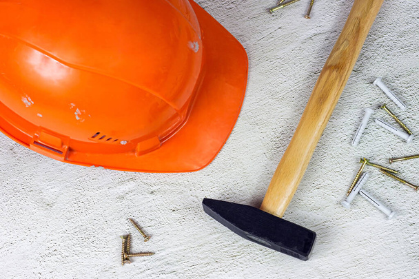 Chapeau protecteur orange avec marteau griffe sur fond ciment gris clair. Réparation et amélioration de la maison, concept de construction de la maison. - Photo, image