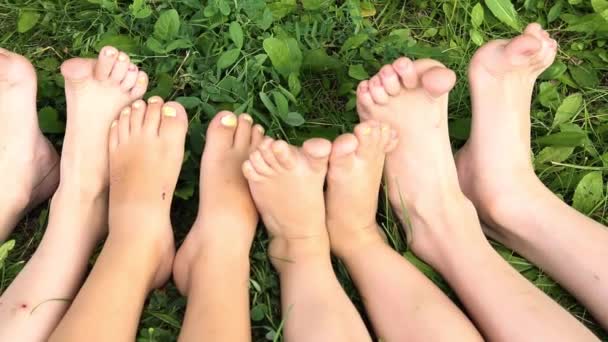 niños sentados en fila con los pies desnudos en la hierba  - Metraje, vídeo