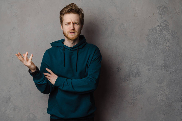 White ginger man with beard frowning and gesture at camera isolated over grey background - Foto, imagen