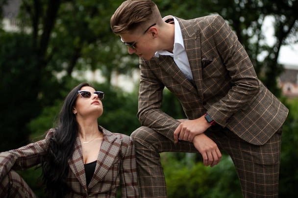 young couple in sunglasses and a woman in a suit and a jacket on a walk in the park - Foto, afbeelding