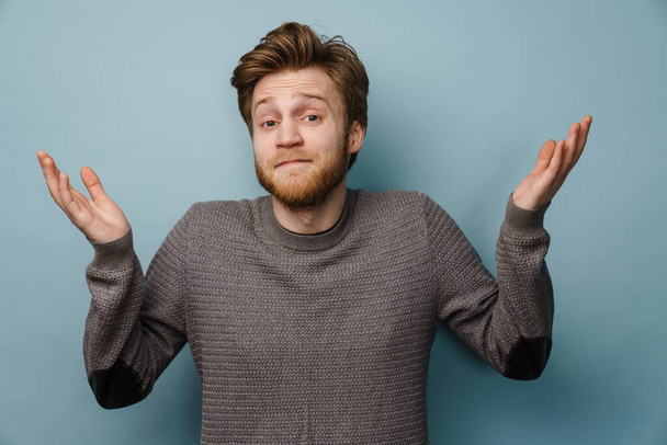 White ginger man with beard gesturing and looking at camera isolated over blue background - Foto, Bild
