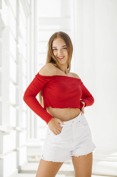 Portrait of a young beautiful blonde girl in white jeans short - Фото, зображення