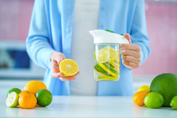 Woman holds glass jug with refreshing infused detoxification citrus water for vitamin detox drink. Slimming antioxidant drinks for diet healthy drinking  - Foto, immagini