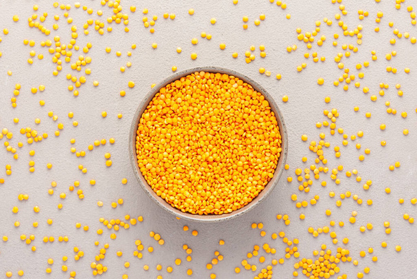 Legumes in bowl and scattered in the background, lentils in a plate on a gray background, top view - Φωτογραφία, εικόνα