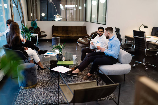 Smart multiracial colleagues in elegant outfit gathering together for discussing strategy of business project in convenient modern hall with furniture - Photo, image