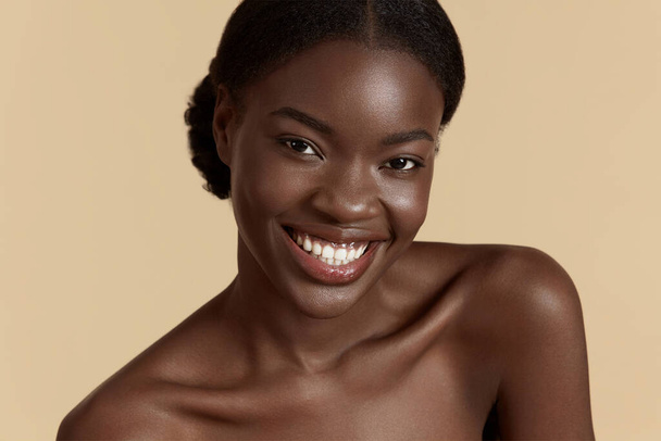 Portrait close up of beautiful african girl. Smiling young woman looking at camera. Concept of skincare. Isolated on beige background. Studio shoot - Foto, Imagen