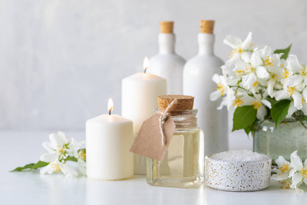Spa concept with jasmine oil, with bath salt and flowers on a white background. Spa and wellness still life. Copy space. - Photo, Image