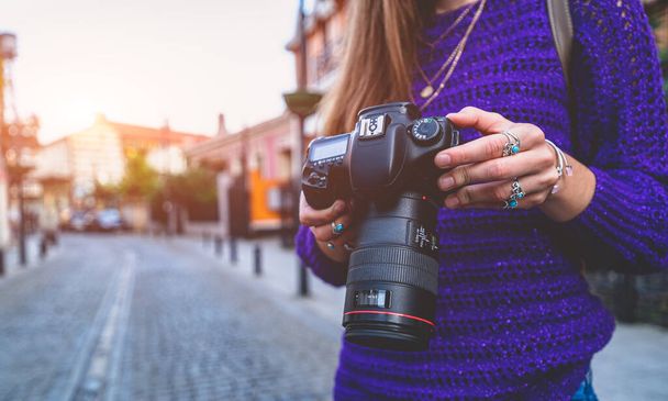 Stylish casual traveler photographer woman taking pictures with digital dslr camera and slr lens during walking around european city - Foto, Imagem