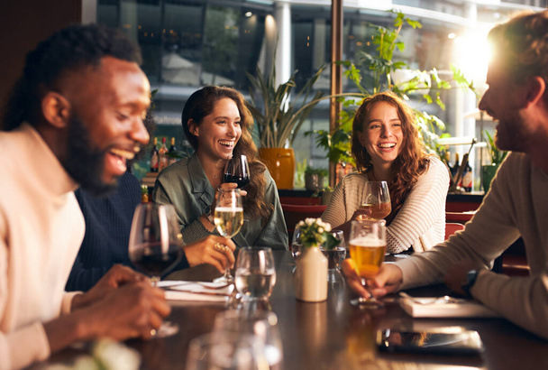 Friends laughing with drinks in bar - Photo, Image