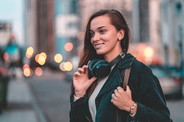 Young happy stylish trendy casual hipster music lover woman teenager with a black wireless headphone during walking around the city.  Enjoying and love music  - Fotoğraf, Görsel