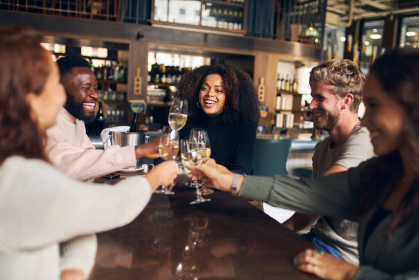 Barátok ünnepelnek borral a bárban - Fotó, kép