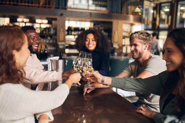 Freunde stoßen mit Wein in Bar an - Foto, Bild