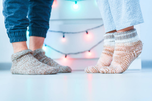 Romantic lovers family couple in warm knitted soft cozy socks in wintertime at home.   - Zdjęcie, obraz