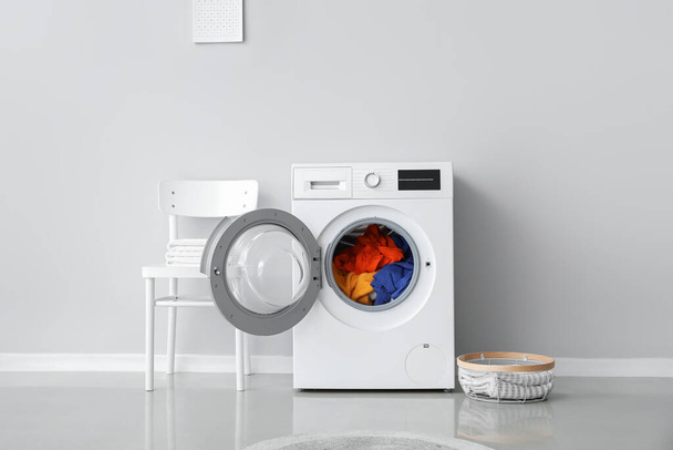 Lavatrice moderna con lavanderia vicino alla parete luminosa - Foto, immagini