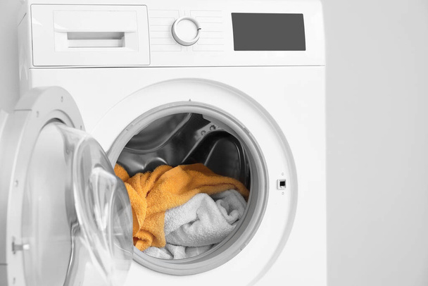 Machine à laver moderne avec buanderie près du mur léger - Photo, image