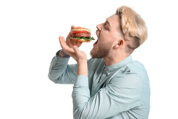 Jongeman eet veganistische hamburger op witte achtergrond - Foto, afbeelding
