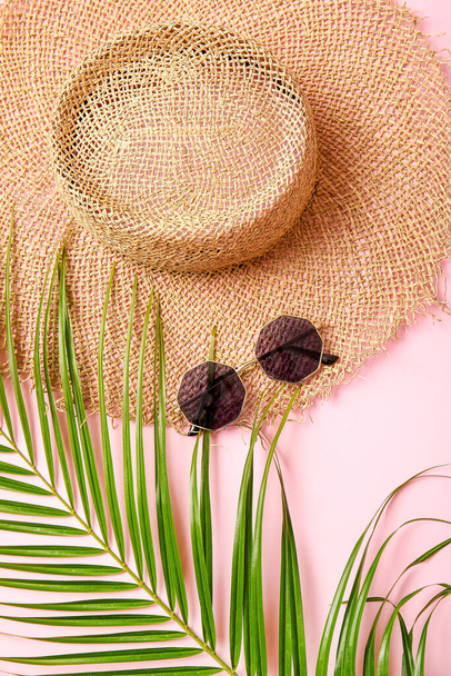 Stylish sunglasses, hat and palm leaf on color background, closeup - 写真・画像