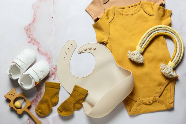 Composition with baby clothes, bib, toys and shoes on light background - Photo, Image