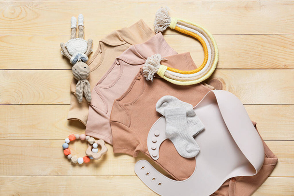 Композиція з дитячим одягом, іграшками та аксесуарами на дерев'яному фоні
 - Фото, зображення