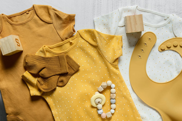 Bebek kıyafetleri, önlük ve oyuncaklar arka planda, yakın plan - Fotoğraf, Görsel
