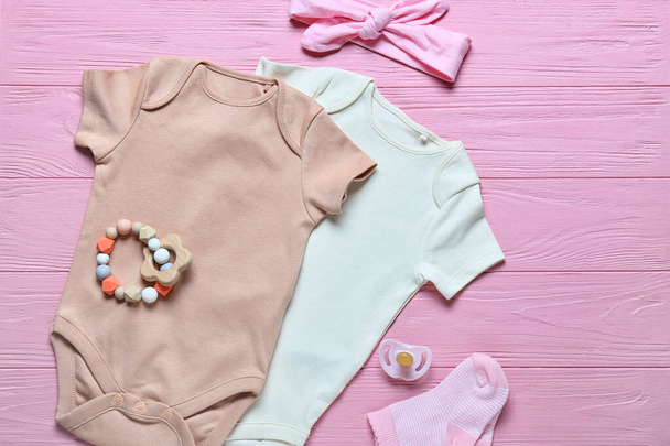 Babybekleidung und Accessoires auf farbigem Holzhintergrund - Foto, Bild