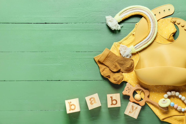 Composición con ropa de bebé, babero y juguetes sobre fondo de madera de color, primer plano - Foto, imagen