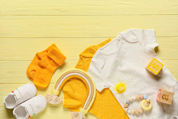 Composición con ropa de bebé, zapatos y accesorios sobre fondo de madera de color, primer plano - Foto, imagen
