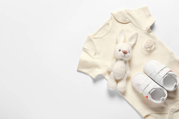 Ropa de bebé, zapatos, juguete y chupete sobre fondo blanco - Foto, imagen