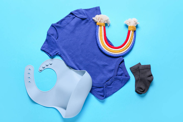 Ubrania dla niemowląt, śliniak i zabawka na tle koloru - Zdjęcie, obraz