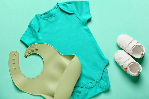 Baby clothes, bib and shoes on color background - Photo, Image