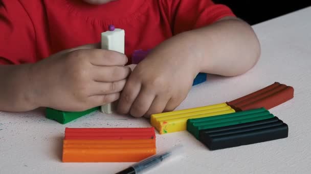 Video, las manos de un niño pequeño esculpiendo de plastilina de colores. Primer plano. - Imágenes, Vídeo