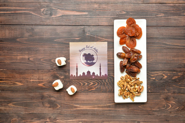 Тай з вітальною карткою для Eid al-Adha (свято жертви) і турецькими солодощами на дерев'яному фоні. - Фото, зображення