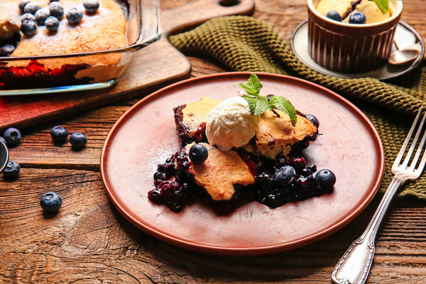 Plate with pieces of blueberry cobbler and ice cream on wooden background, closeup - Zdjęcie, obraz