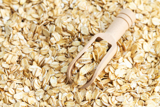 Wooden scoop of dry raw rolled oat flakes top view - Photo, Image