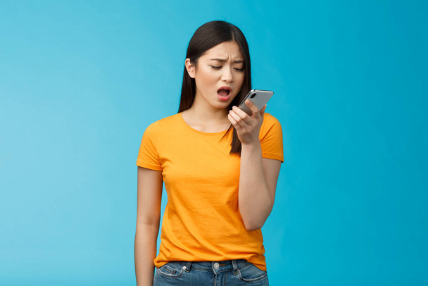 Upset whining displeased moody girlfriend complaining talk into smartphone hold phone near mouth upset, frowning bothered bad connection, record voice message, blue background - Фото, зображення