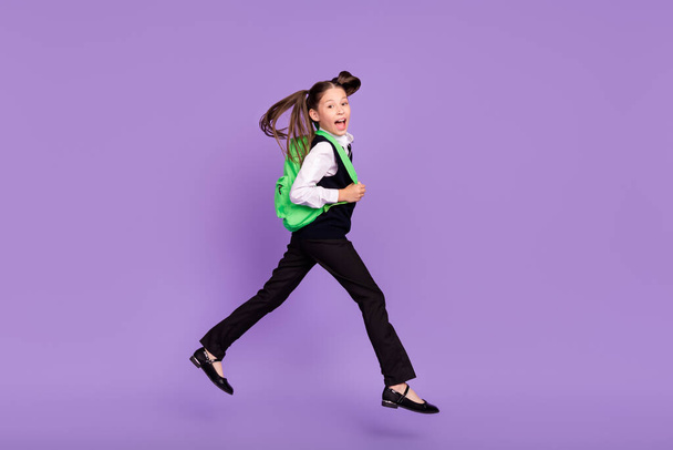 Photo of glad cheerful impressed schoolgirl jump run wear rucksack uniform isolated violet color background. - Foto, afbeelding