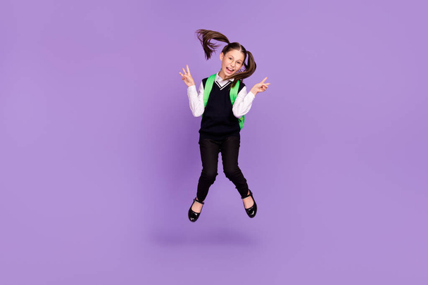 Photo of friendly schoolgirl jump show v-sign wear rucksack glasses uniform isolated purple color background. - Foto, Imagen