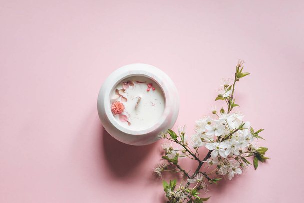 Ecological and vegan handmade candle with dry flowers in a glass made of concrete on a pink background. - Фото, изображение