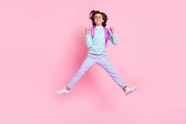 Photo of carefree champion schoolboy jump raise fists wear eyewear rucksack teal shirt isolated pink color background - Fotó, kép