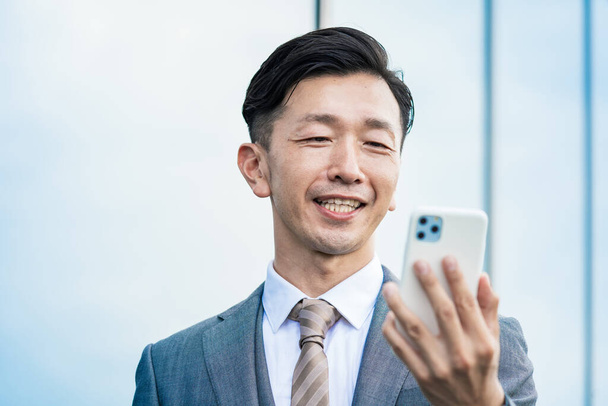 Asijský podnikatel při pohledu na obrazovce smartphone - Fotografie, Obrázek