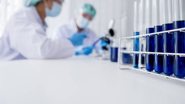 Investigador médico o científico o médico de cabecera mirando un tubo de ensayo de solución transparente en un laboratorio - Foto, imagen
