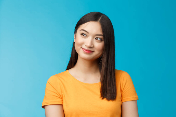 Close-up dreamy hopeful charming young asian woman wear yellow t-shirt turn sideways smiling delighted, contemplate beautiful summer scenery outside window sit office carefree, blue background - Fotografie, Obrázek