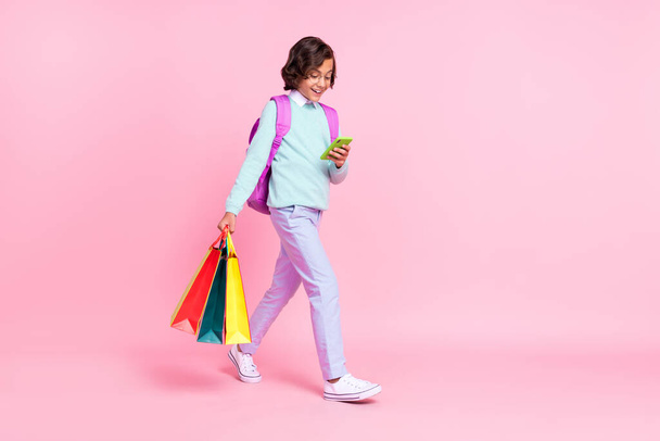 Photo of client schoolboy walk hold bags blog phone wear bag specs teal shirt isolated pink color background - 写真・画像